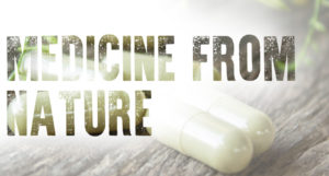 Text Medicine From Nature overlaying herbal capsules on wooden table outside